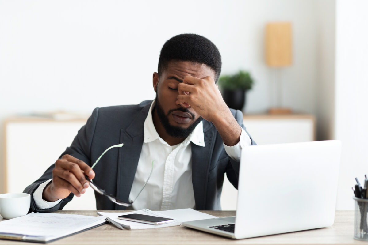 Overworked businessman sitting at workplace after hard day in office Overworked african american businessman sitting at workplace after hard day in office, panorama